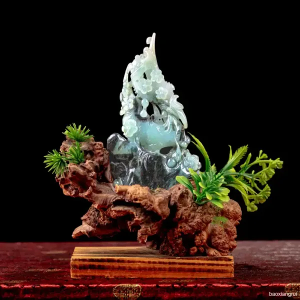 Carved jade figurine with wooden base and greenery.