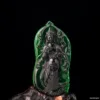 Carved jade sculpture of a deity on black background.