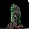 Carved green jade Guanyin statue on black background.