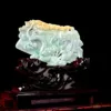 Carved jade dragon sculpture on wooden stand.