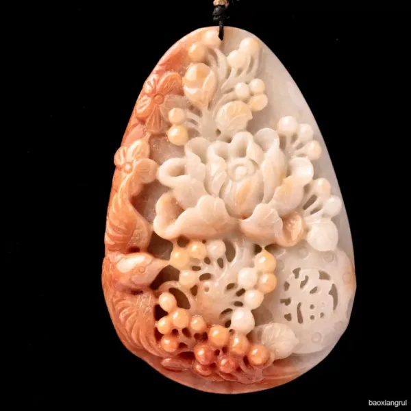 Carved jade pendant with floral design against black background.