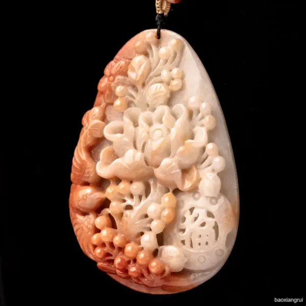 Carved jade pendant with floral design on black background.