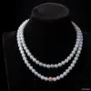 Double strand pearl necklace with pink gemstone centerpiece.