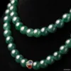 Elegant jade necklace with decorative clasp on black.