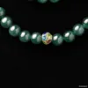 Green bead necklace with colorful central ornamental bead.