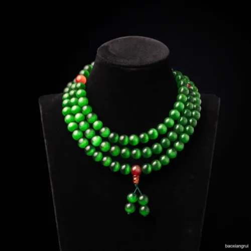 Green beaded necklace on black display stand.