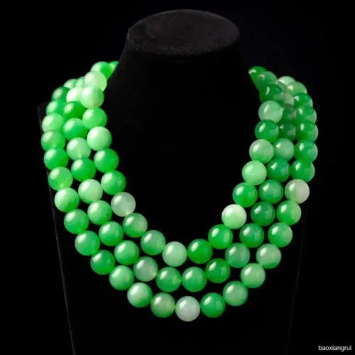 Green bead necklace on black display stand.