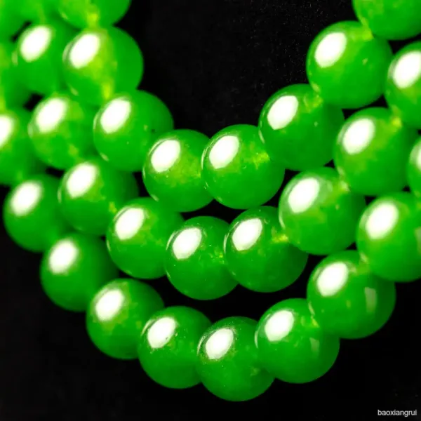 Green jade beads close-up on black background.