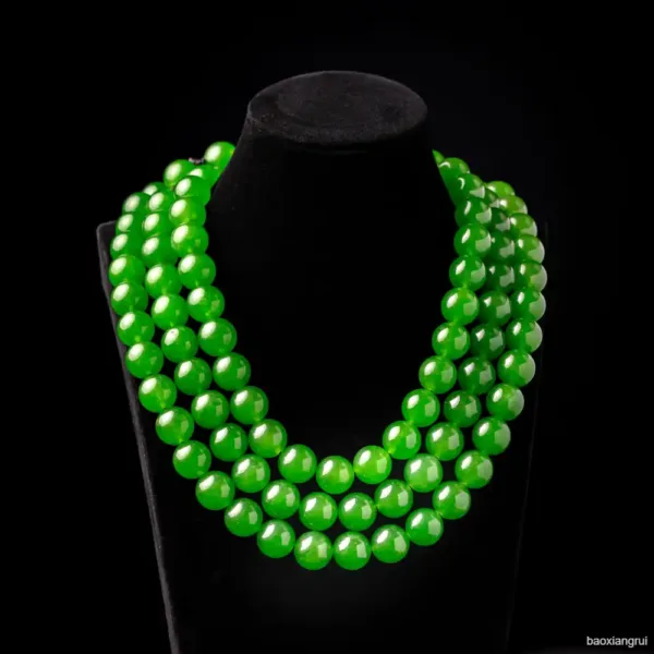 Green beaded necklace on black display stand.