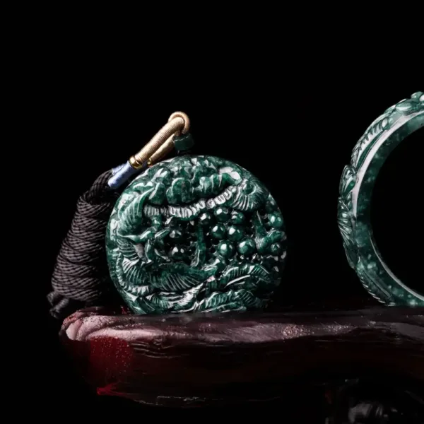 Carved jade pendant with intricate design on black background.