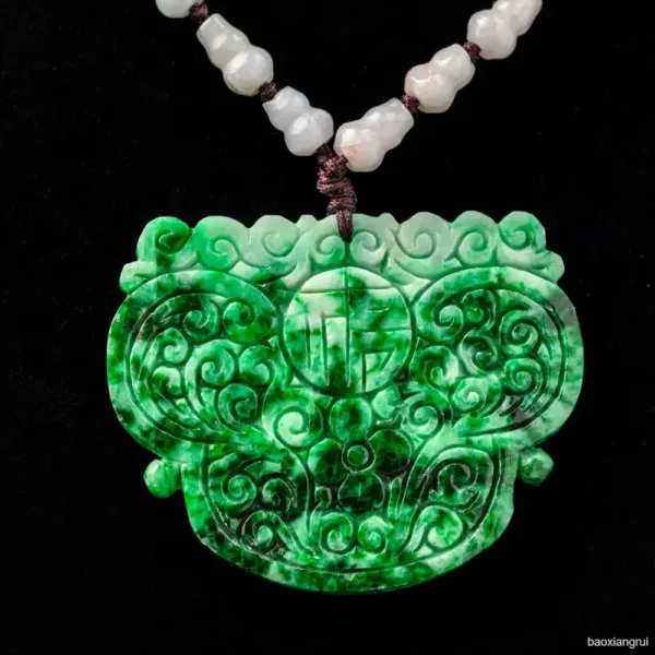 Carved jade pendant on black background.