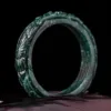 Carved jade bracelet on dark background.