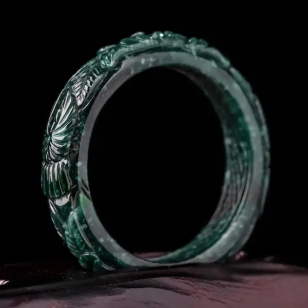 Carved jade bracelet on dark background.