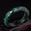 Carved green jade bangle bracelet on dark background.