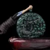 Carved jade pendant with sword hilt on black background.