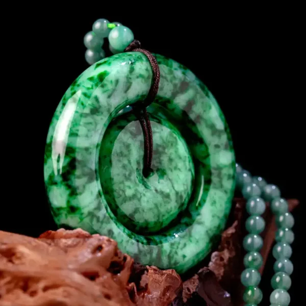 Jade pendant with beads on dark background.