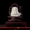 White jade Buddha statue on wooden stand.