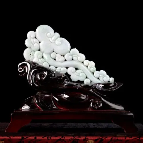 Jade carving of clouds on wooden base.